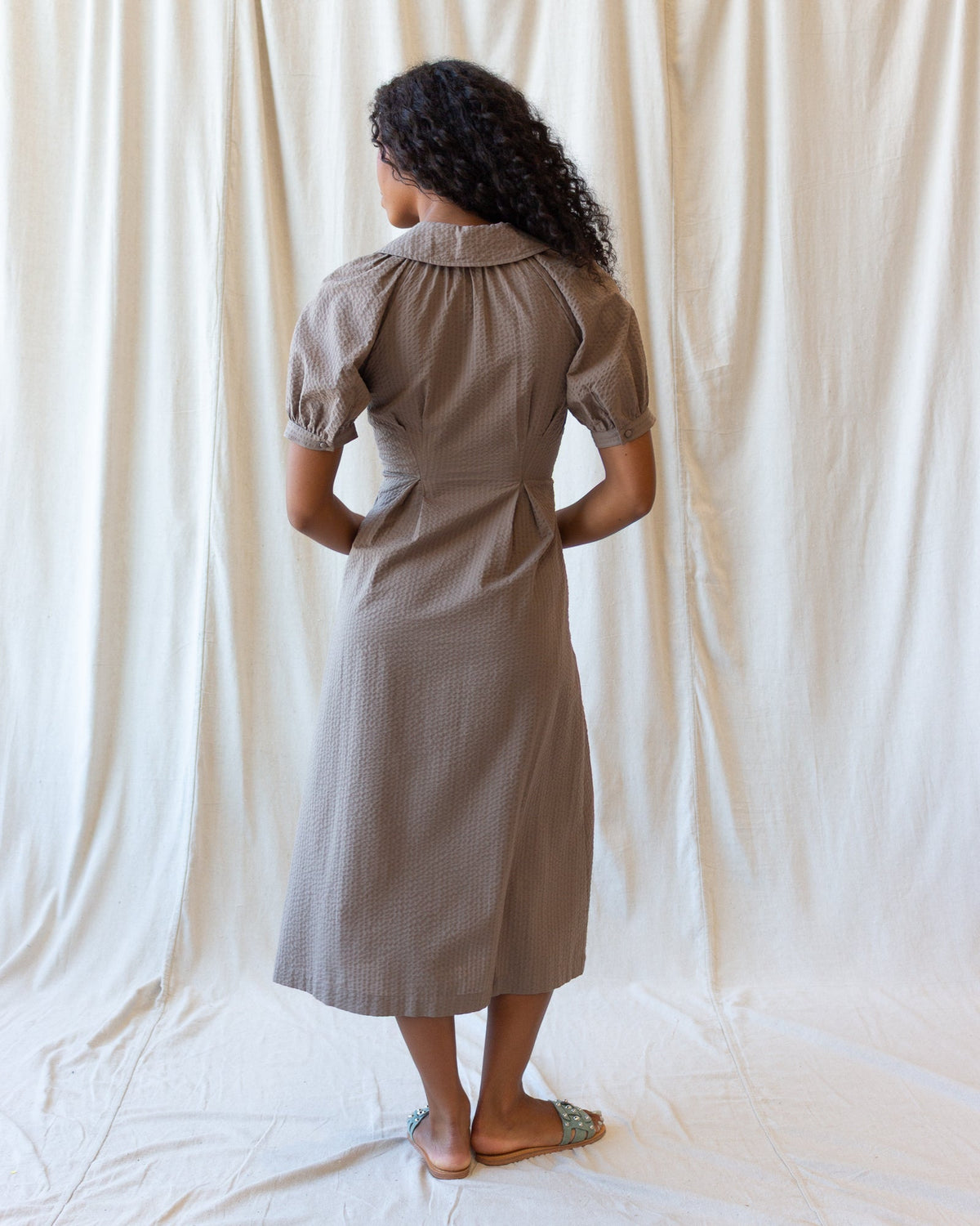 Back view of brown midi field dress with short sleeves and button-free yoke