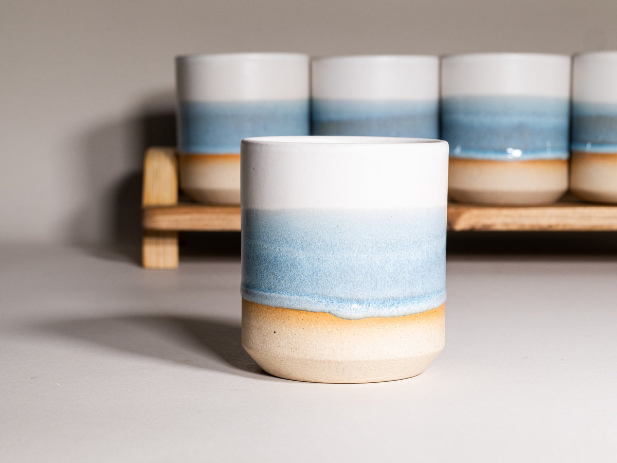 Ice blue and white stoneware smoothie cup with ombre glaze, on display