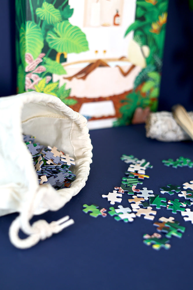 Jigsaw puzzle pieces on tabletop with open fabric bag and box behind