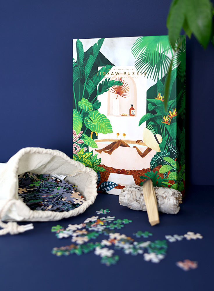 Tropical jigsaw puzzle box with open fabric bag and scattered puzzle pieces