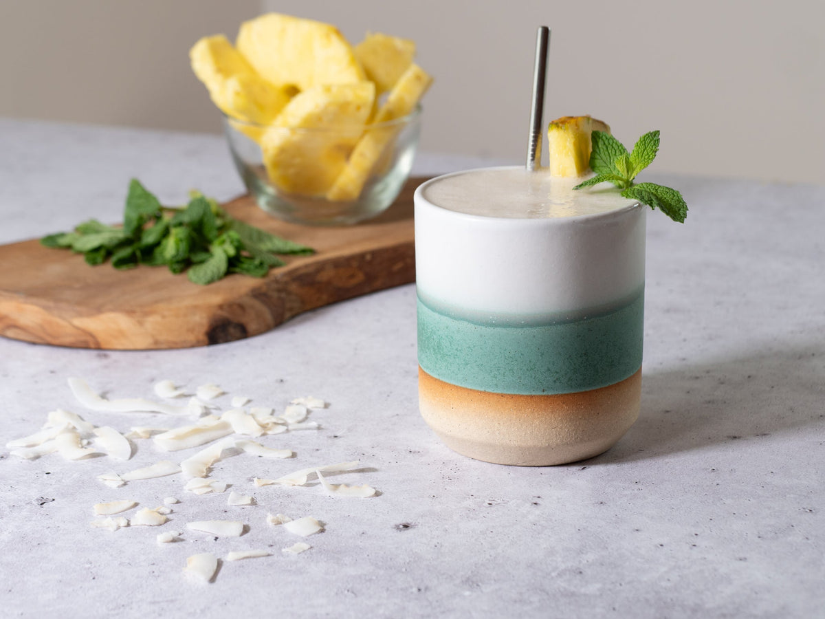 Green and white stoneware smoothie cup, 14 oz, with straw and mint garnish.