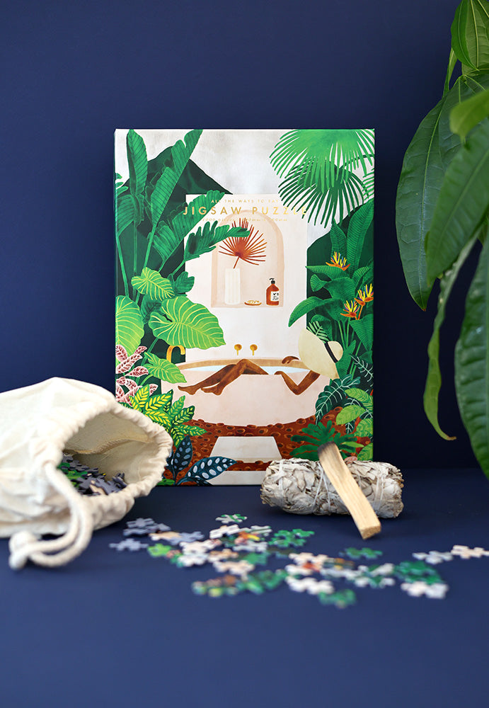 Tropical jigsaw puzzle box with loose pieces on tabletop and open fabric bag