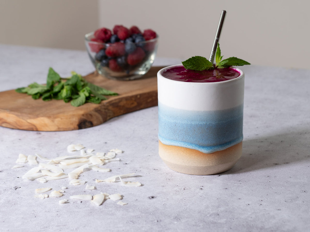 Ice blue and white stoneware smoothie cup filled with red berry smoothie