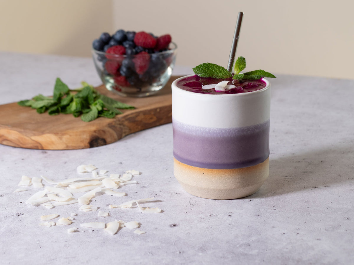 Stoneware smoothie cup with purple-white ombre glaze, filled drink with mint garnish
