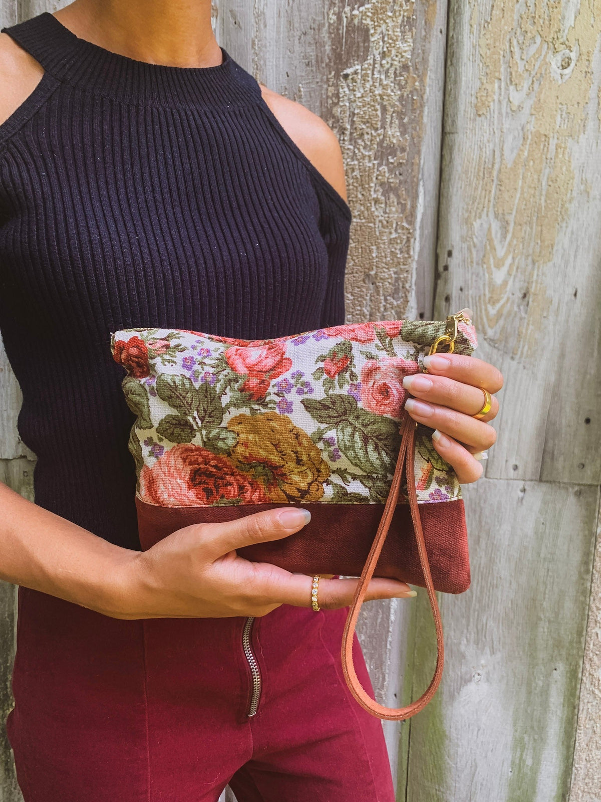 Floral print wristlet purse with brown suede panel and gold wrist strap clasp.