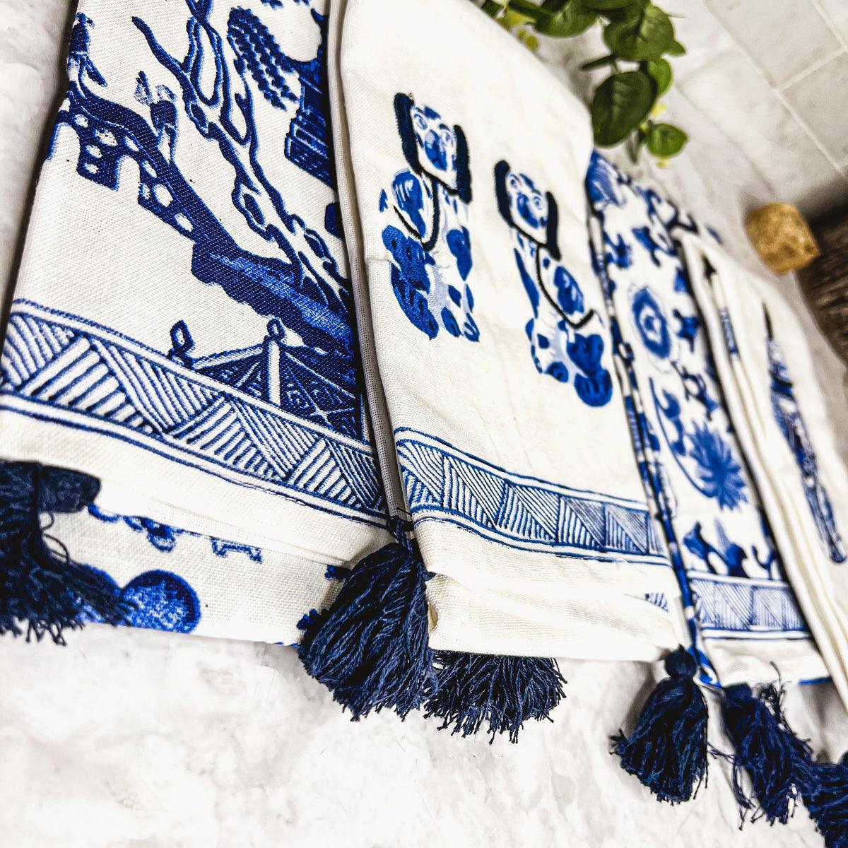 Close-up of blue-and-white chinoiserie tea towel with striped border and dark fringe