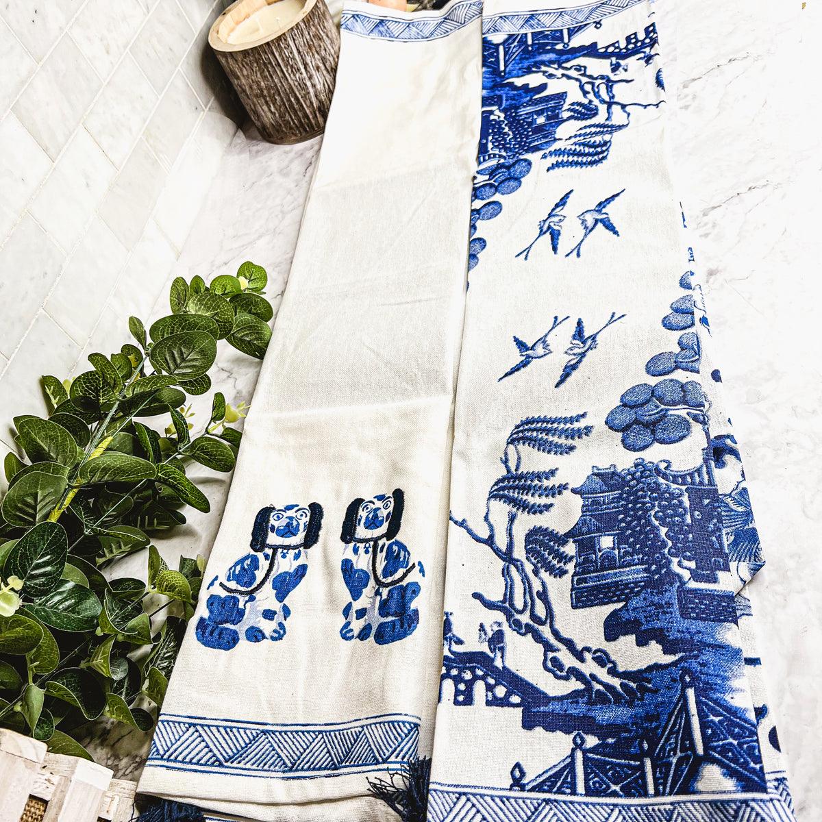 Blue-and-white chinoiserie tea towel with illustrated scene and striped bottom border