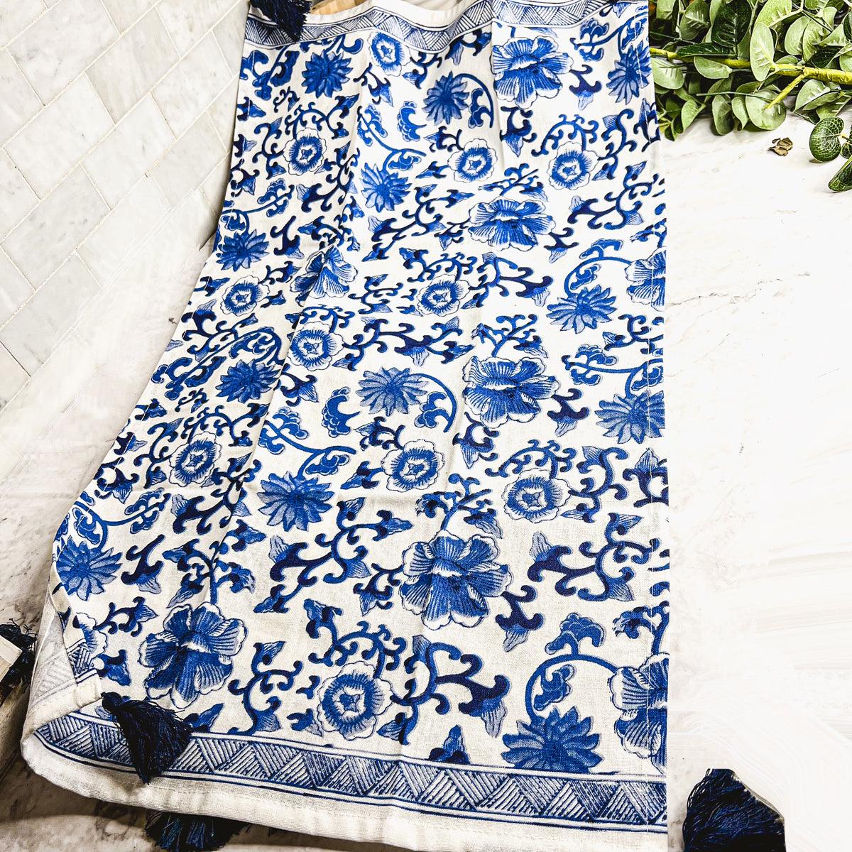 Blue-and-white chinoiserie tea towel with dense floral pattern and fringed hem border