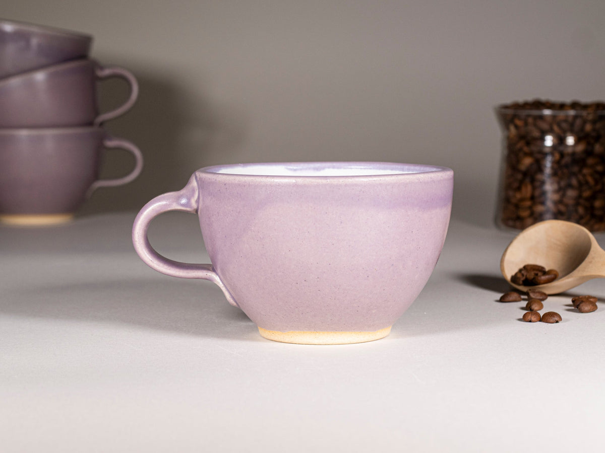 Purple stoneware latte cup with handle, cream-toned base, set shown with other cups
