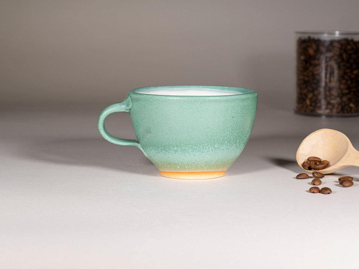 Green stoneware latte cup with handle and speckled glaze, wide rim