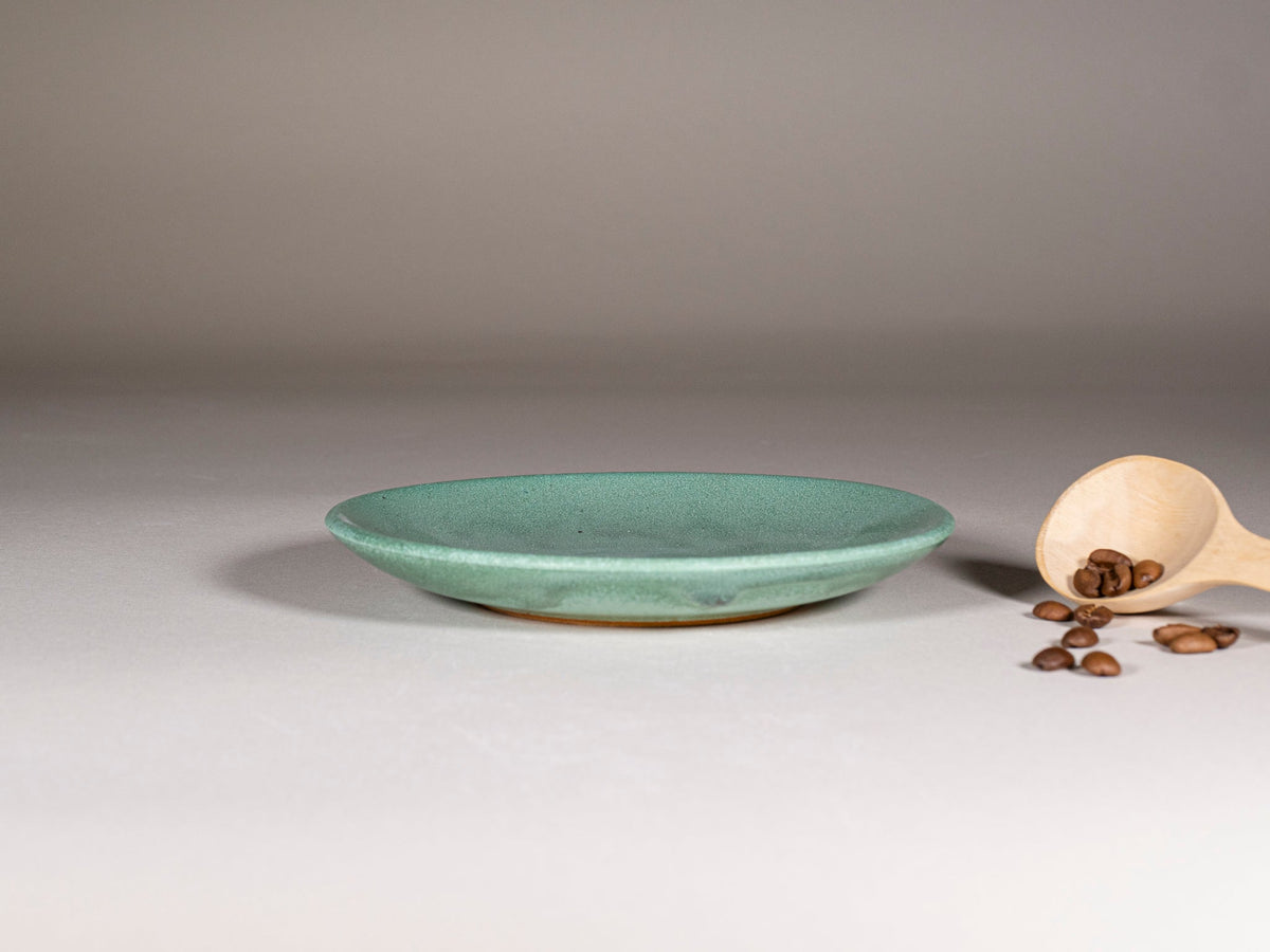Green stoneware saucer plate with speckled glaze