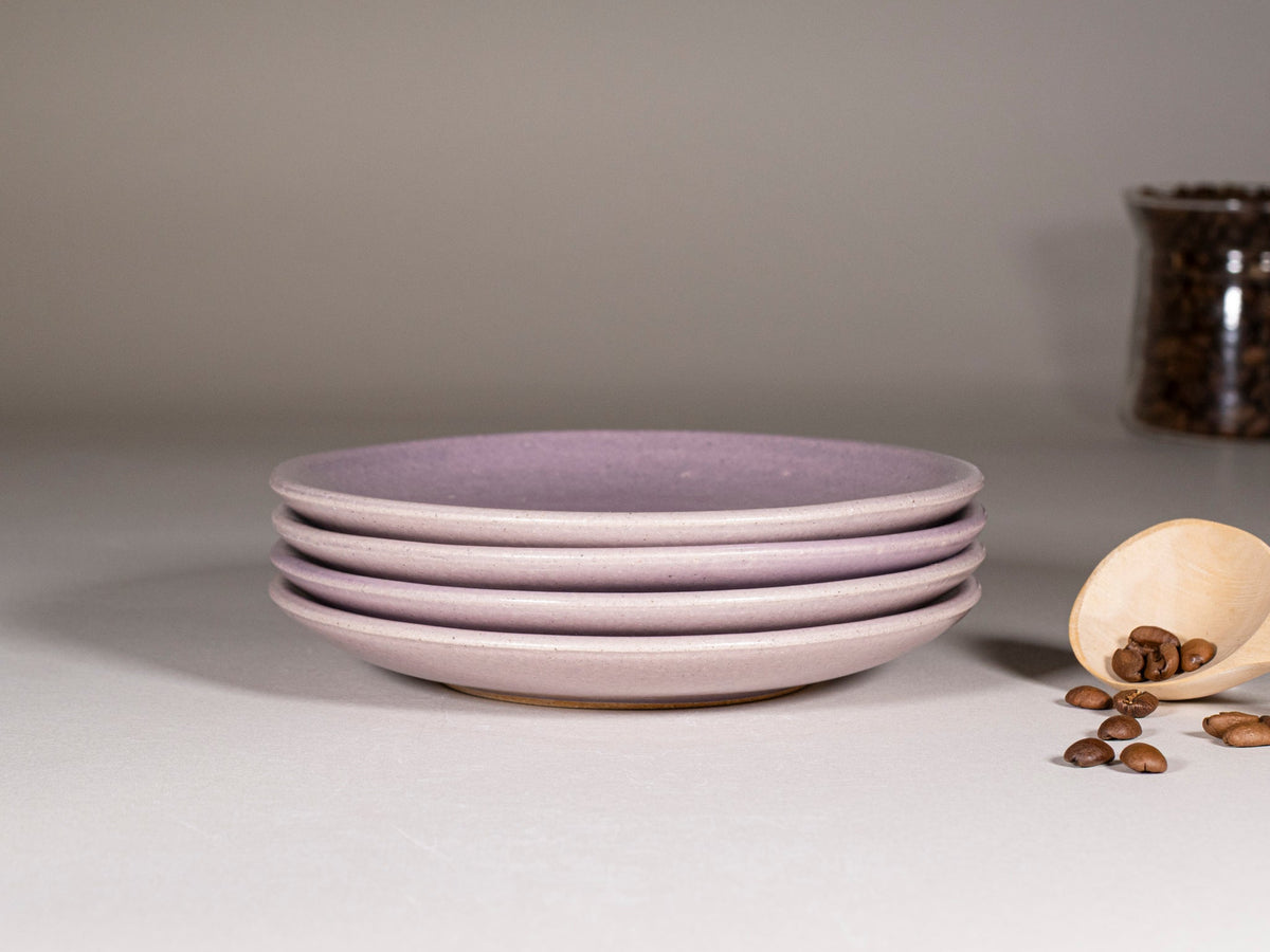 Stack of purple stoneware saucers with pale rim, set of matching plates.