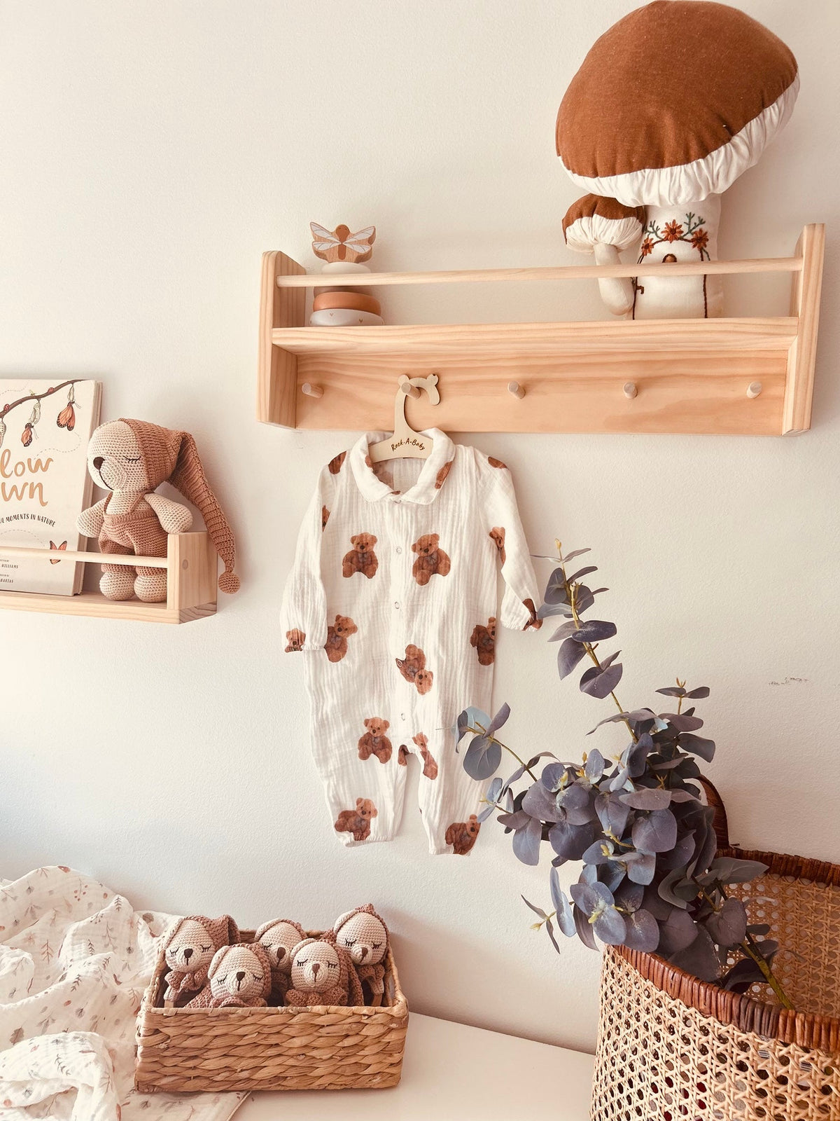 Bear-print baby romper with long sleeves and button front on a wooden hanger