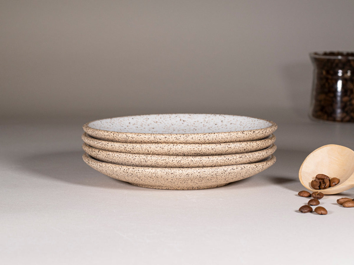 Stack of speckled stoneware saucers, round plates, white with speckles