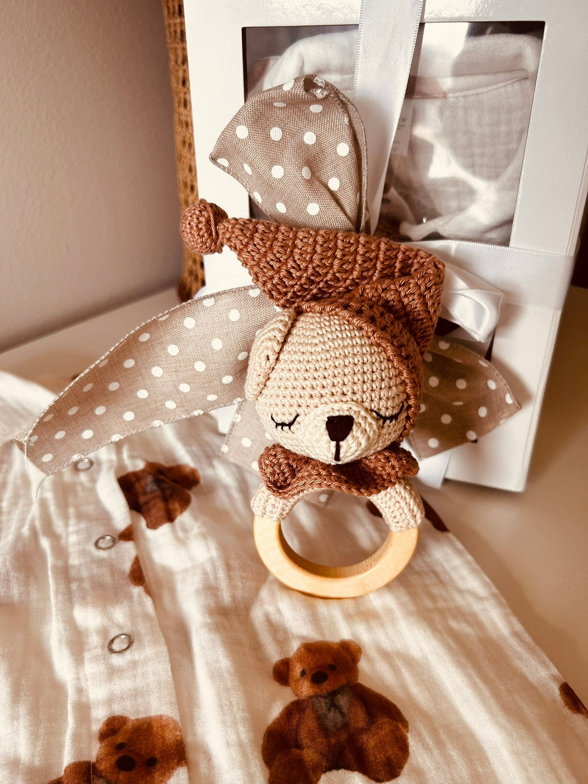 Plush teddy bear rattle with polka-dot fabric ears on bear-print romper