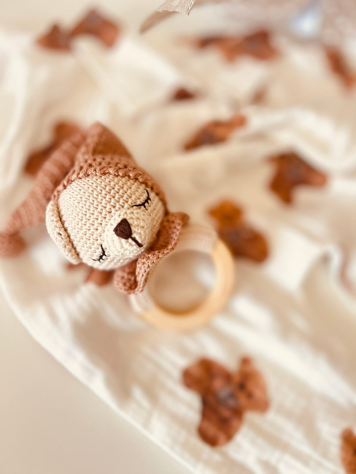 Teddy bear rattle toy with fabric face and round teething ring on baby cloth