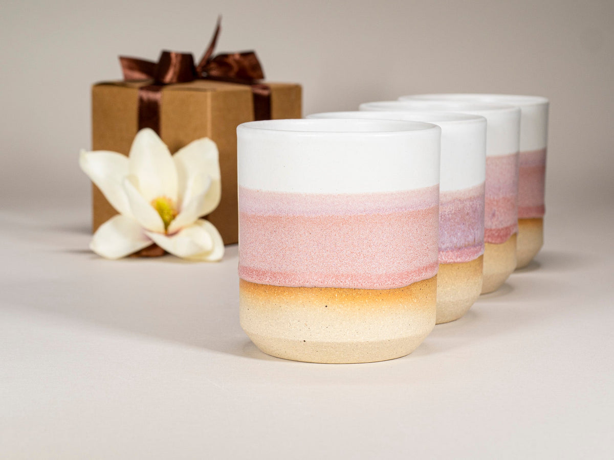 Pink and white stoneware cups with ombre pink band, front view of three