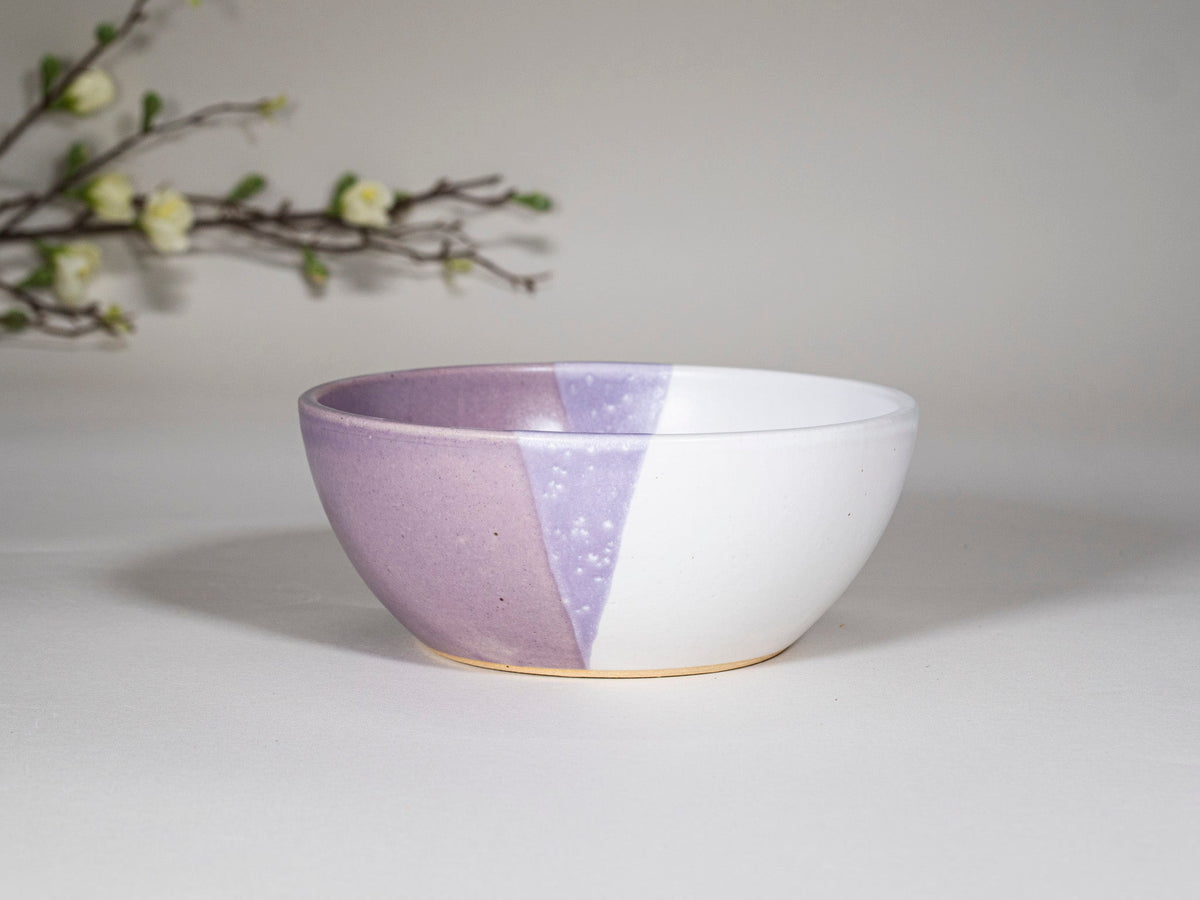 Purple and white stoneware soup bowl with speckled panel, front side view
