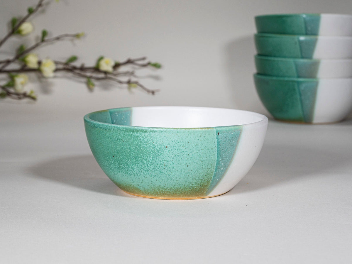 Green speckled stoneware soup bowl with white rim, front view