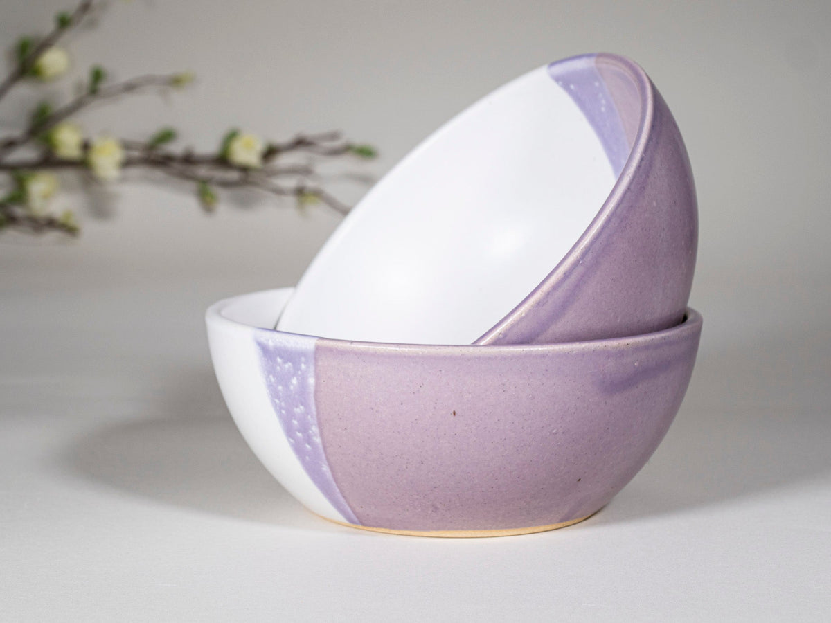 Purple and white stoneware soup bowl with speckled inlay, tilted close-up