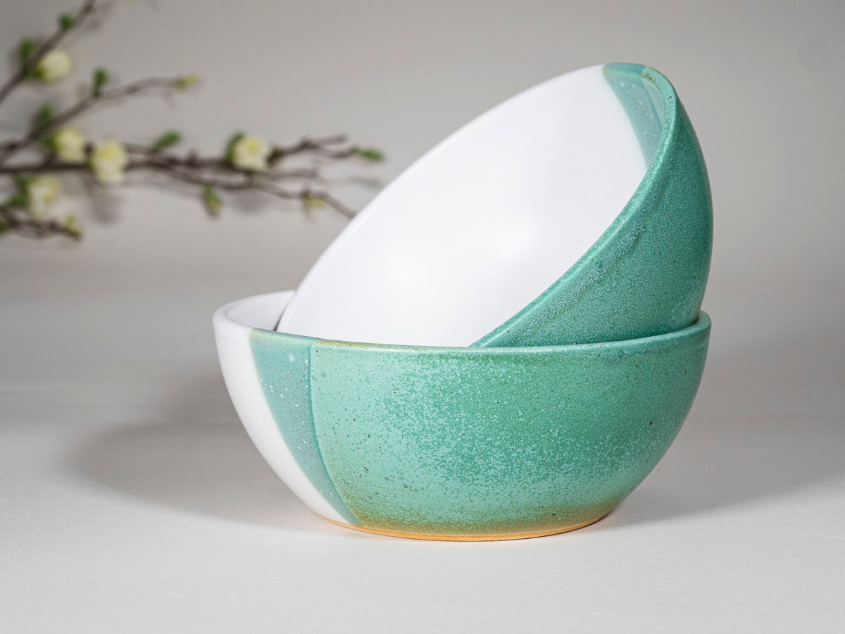 Green and white stoneware soup bowls stacked, tilted angle