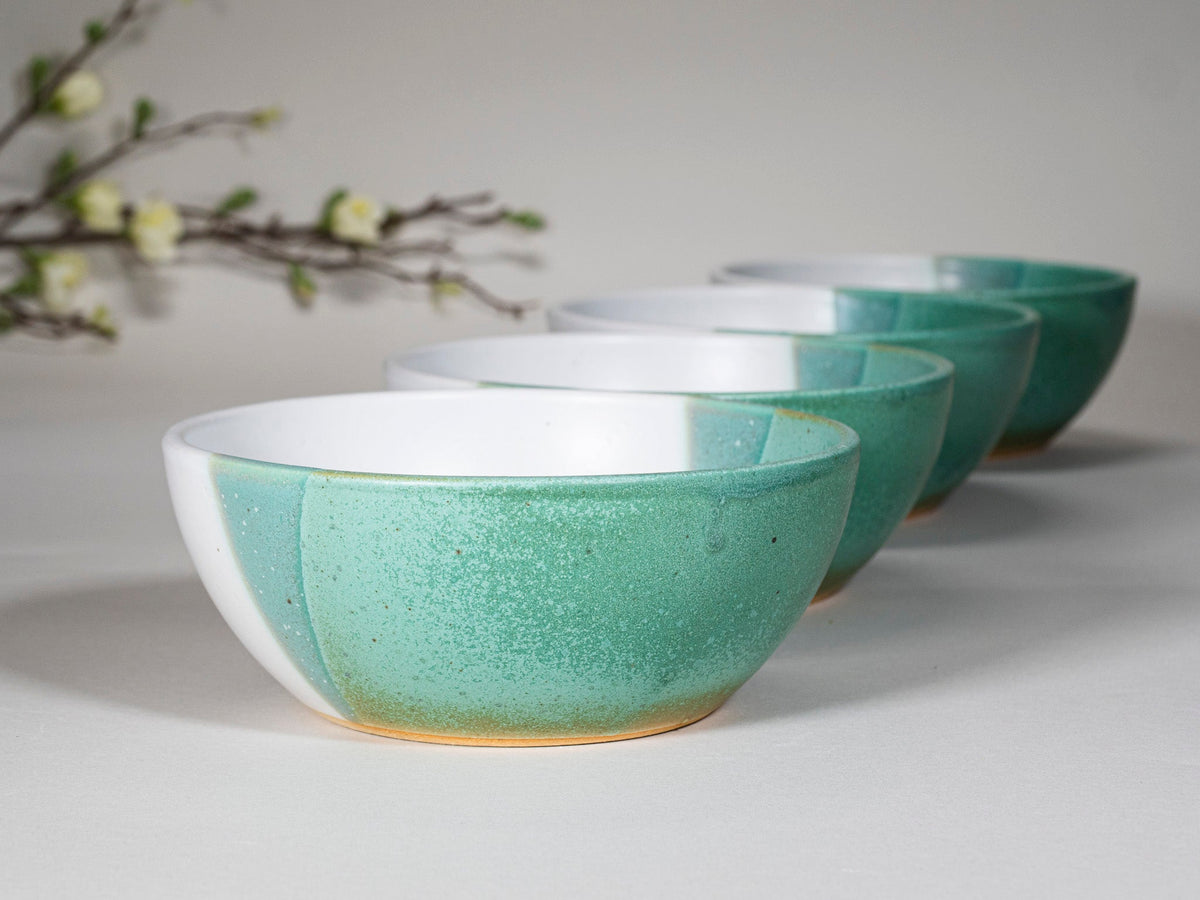 Set of green and white stoneware soup bowls in staggered arrangement