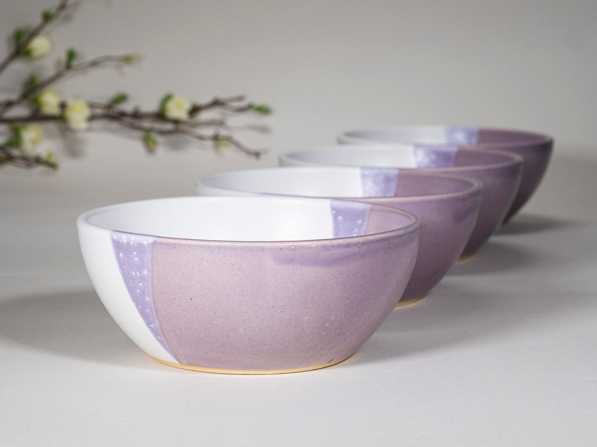 Purple and white stoneware soup bowls, stacked with wide rims