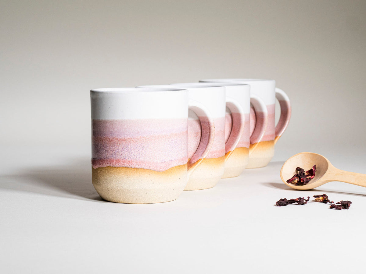 Set of pink-and-white striped ceramic mugs with handles, stacked and angled