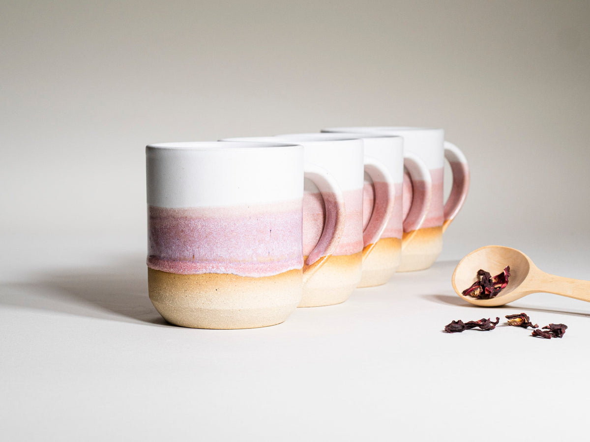 Several pink-and-white striped ceramic coffee mugs with handles, arranged together