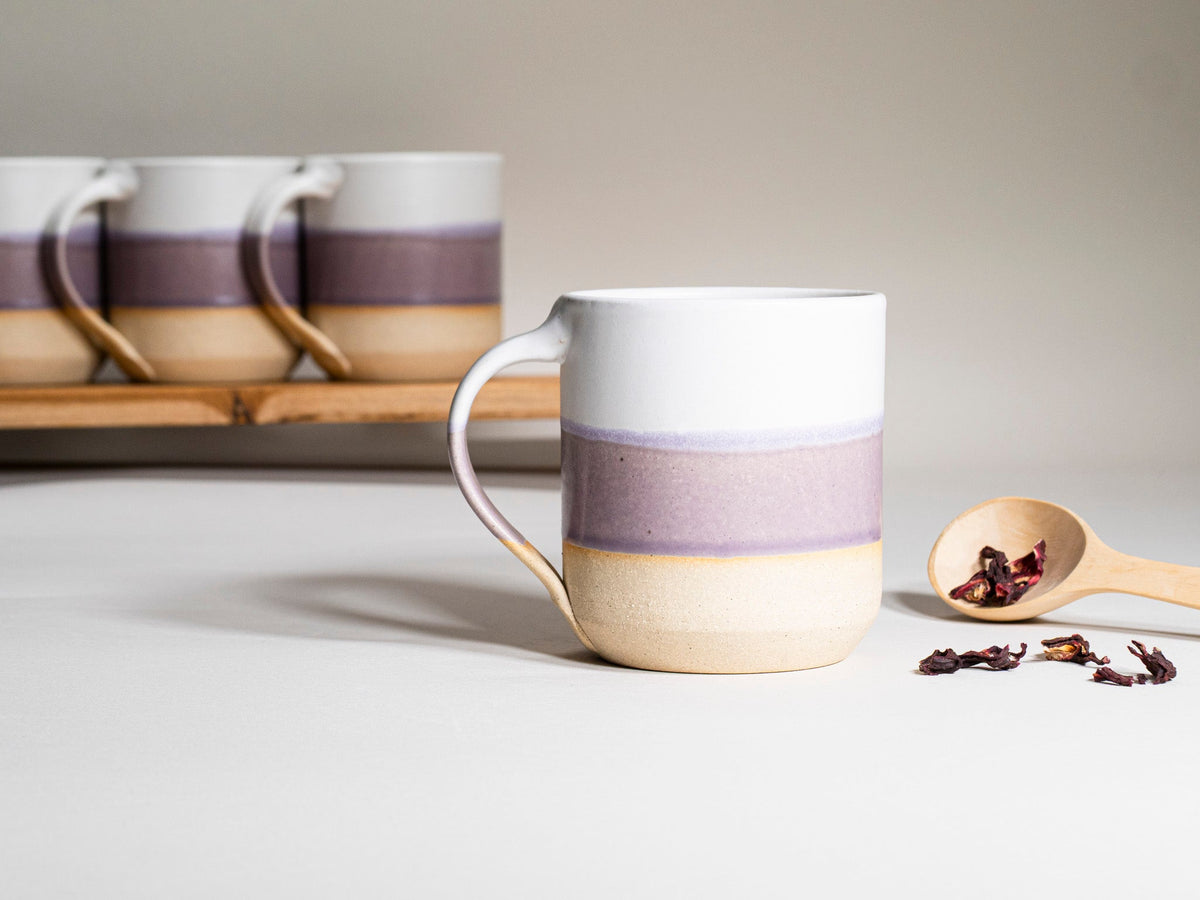 Purple and white ceramic coffee mug with handle, 14 oz, angled view with banded glaze.