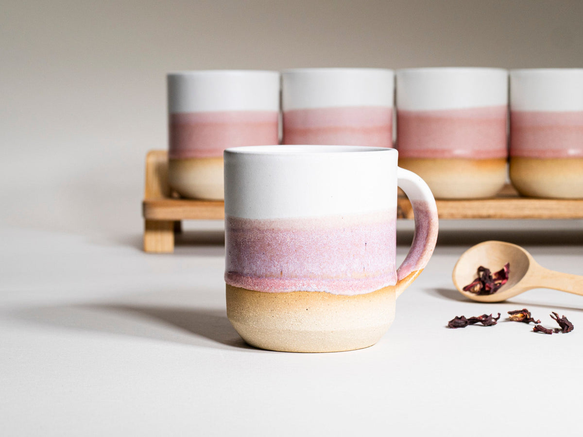 Front pink-and-white striped ceramic mug with handle, with other mugs behind