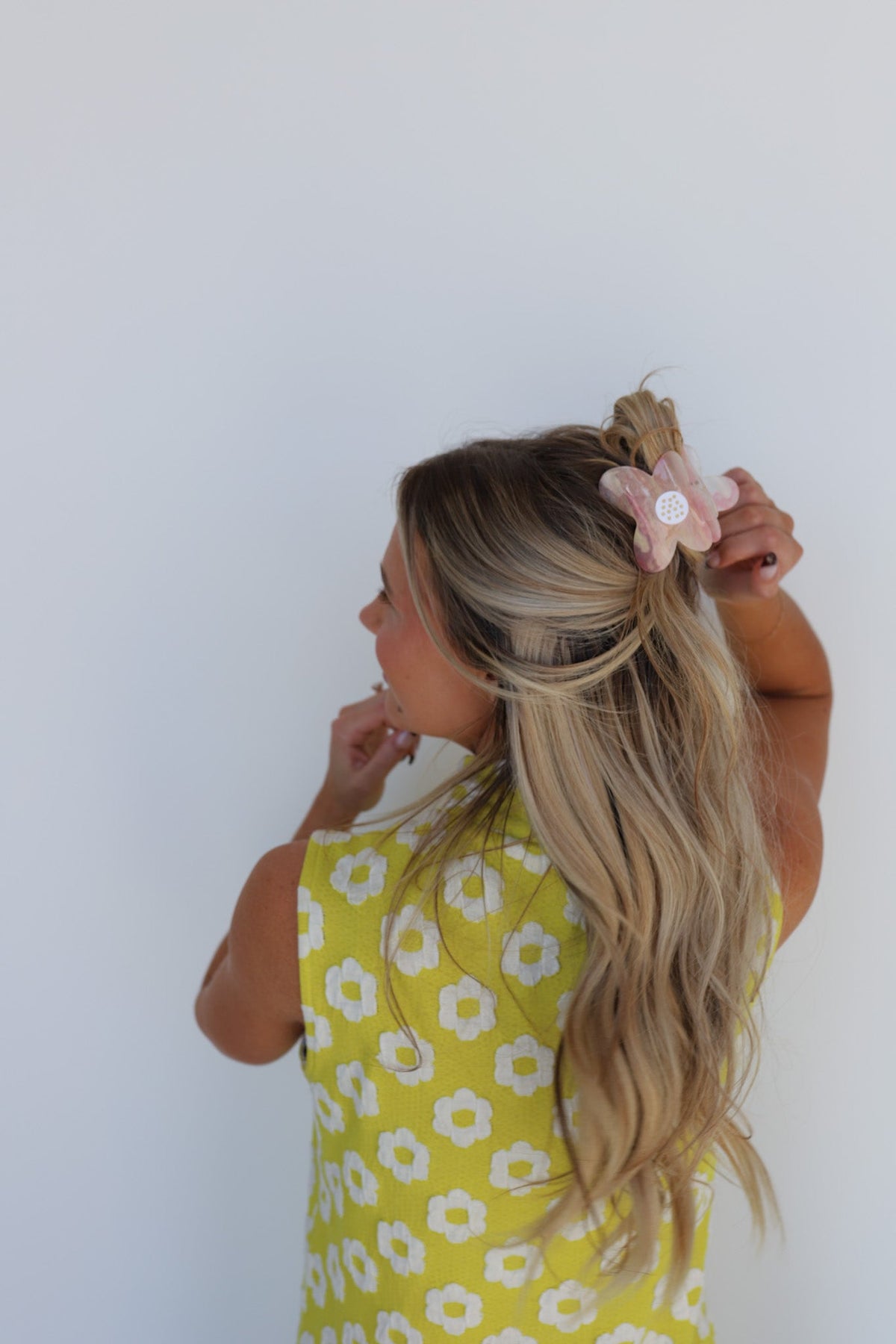 Floral hair claw clip with pink petals on blonde hair; yellow floral dress