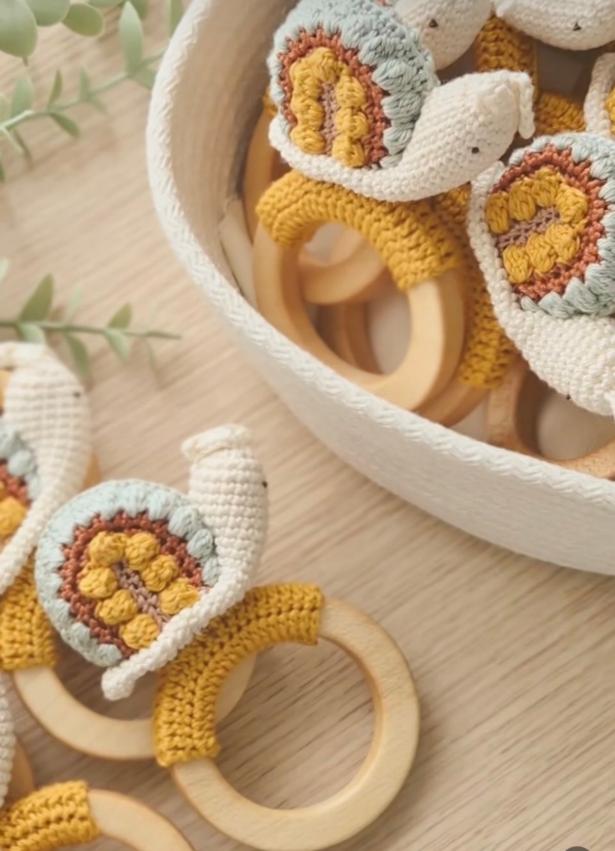 Crocheted snail rattle with round wooden ring and textured yellow and white body