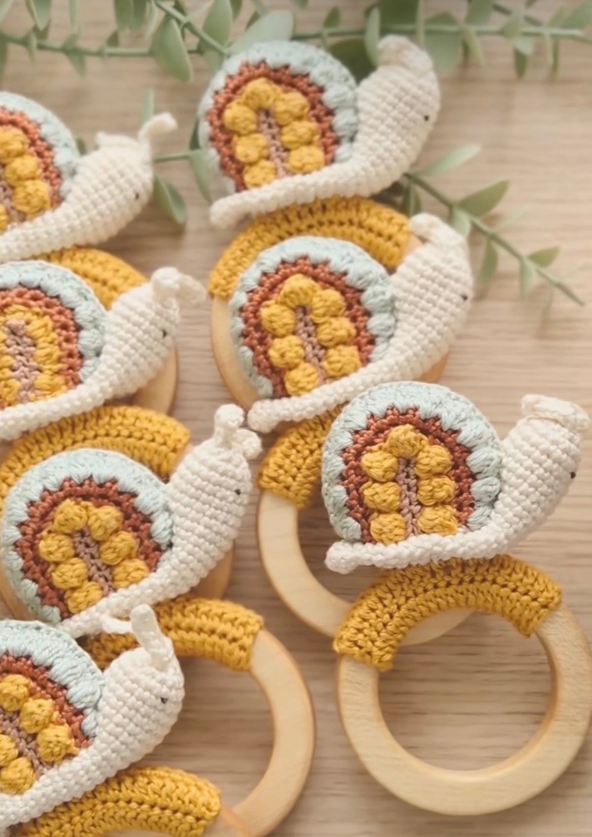 Set of crocheted snail rattles with wooden rings, white, yellow, and brown accents