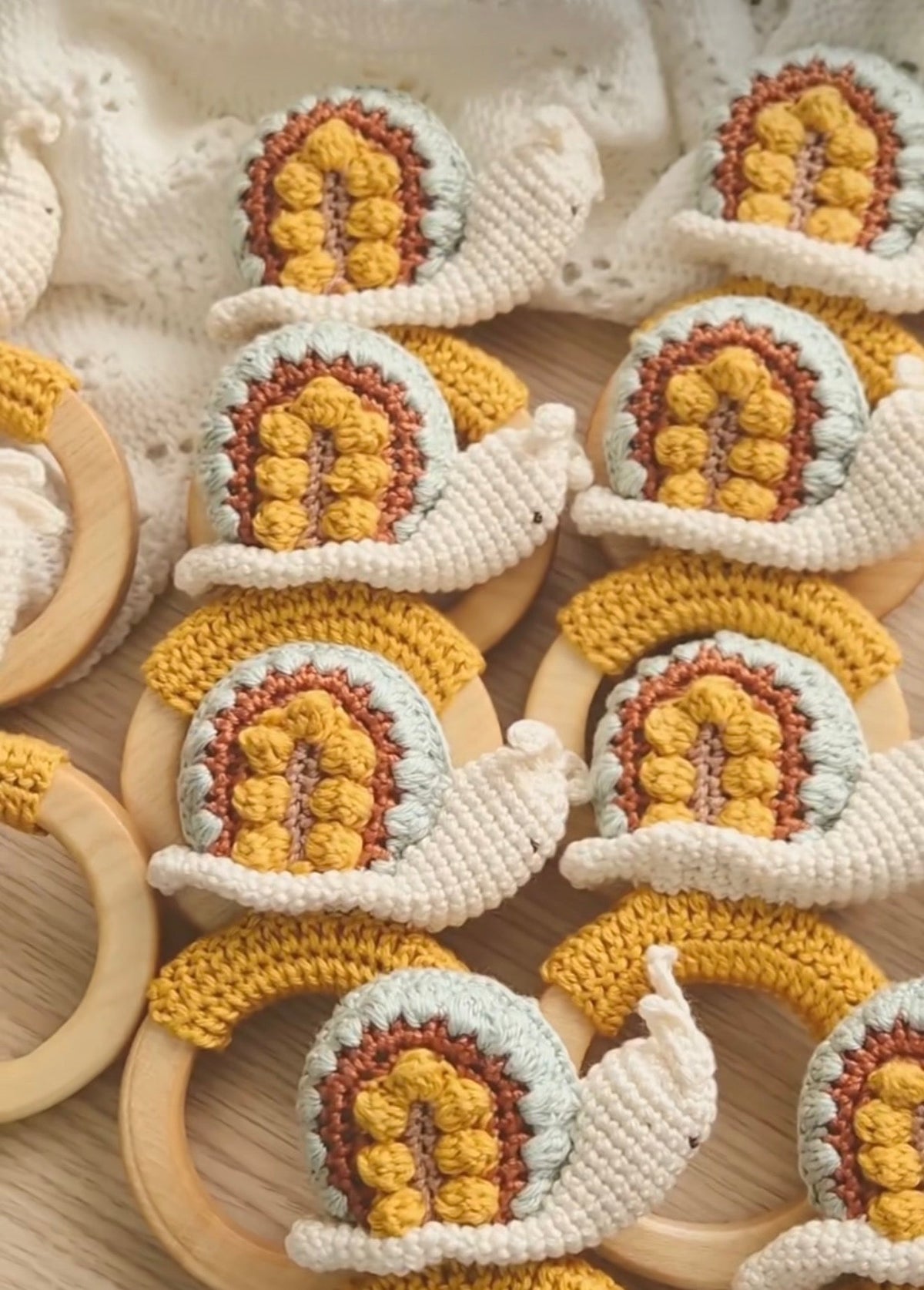 Crocheted snail rattle toys with wooden teething rings and yellow center details