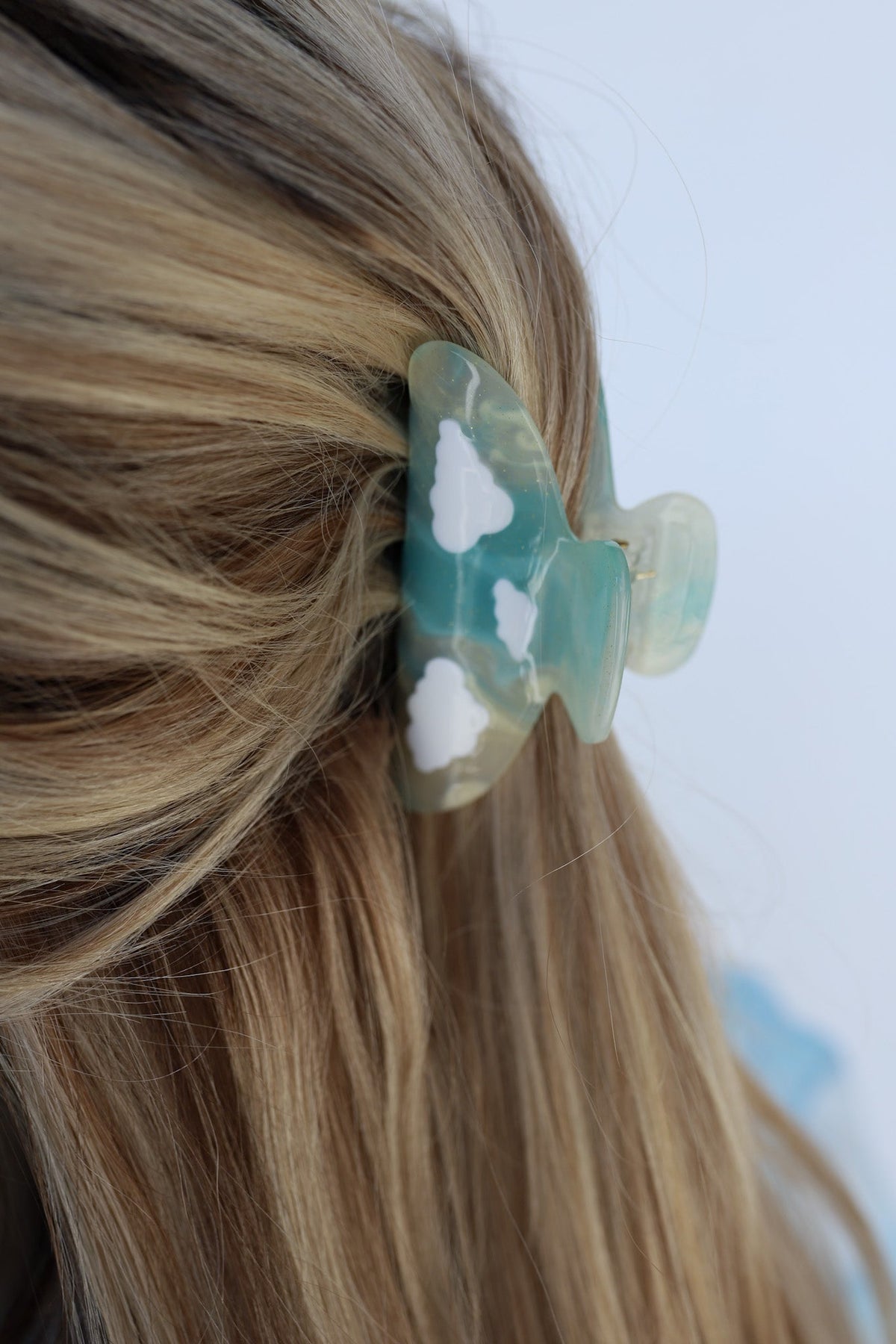 Translucent teal-blue hair claw clip on blonde hair