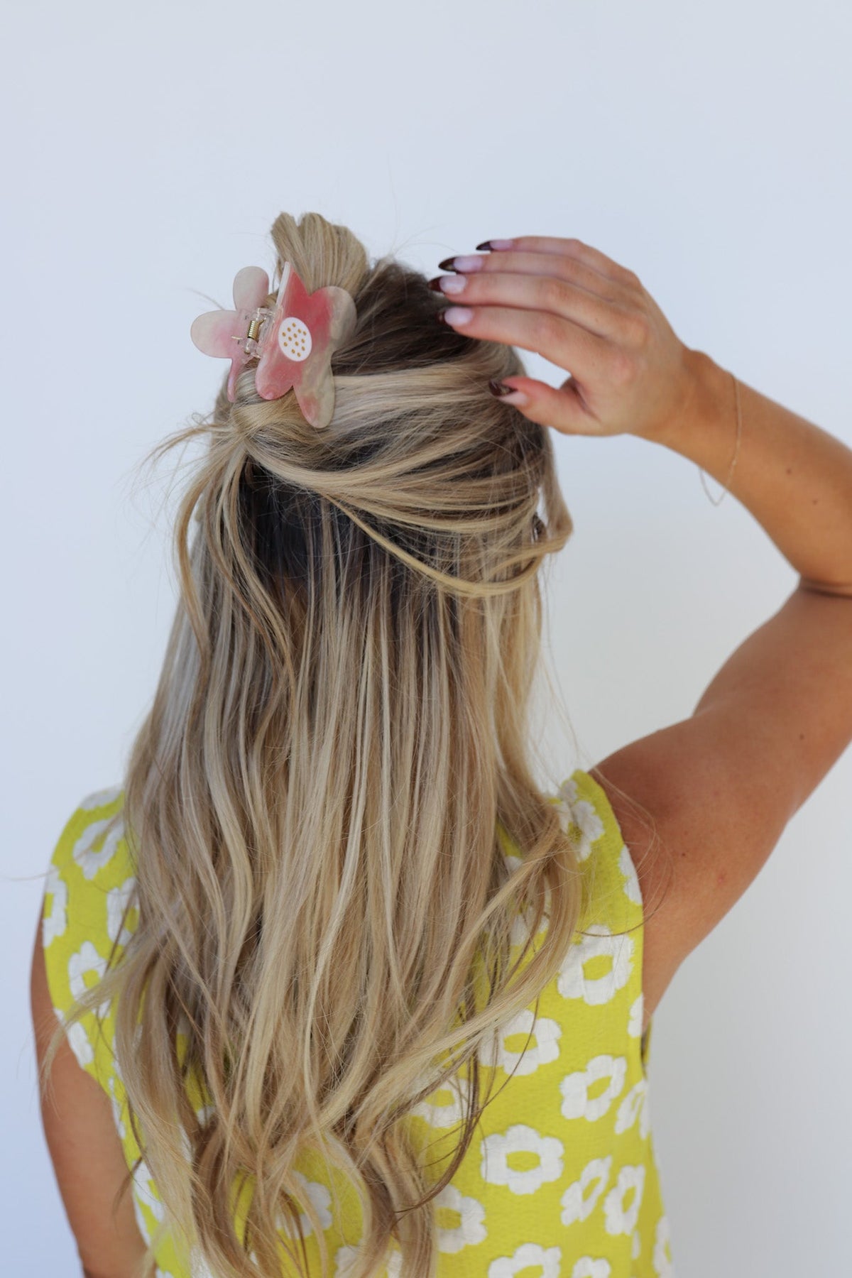 Floral hair claw clip on blonde hair with pink flower accent; yellow dress