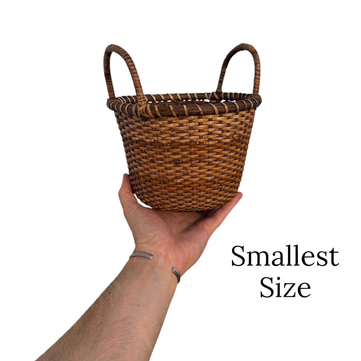 Small woven rattan produce basket with two loop handles, held by hand