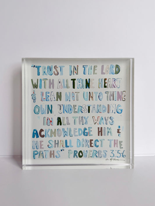 Clear acrylic tabletop art in angled view with multicolor scripture text, Proverbs 3:5-6.