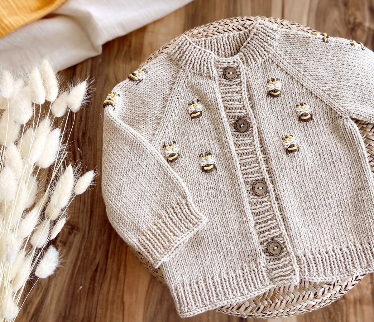 Light beige knit baby cardigan sweater with bee appliques and button placket