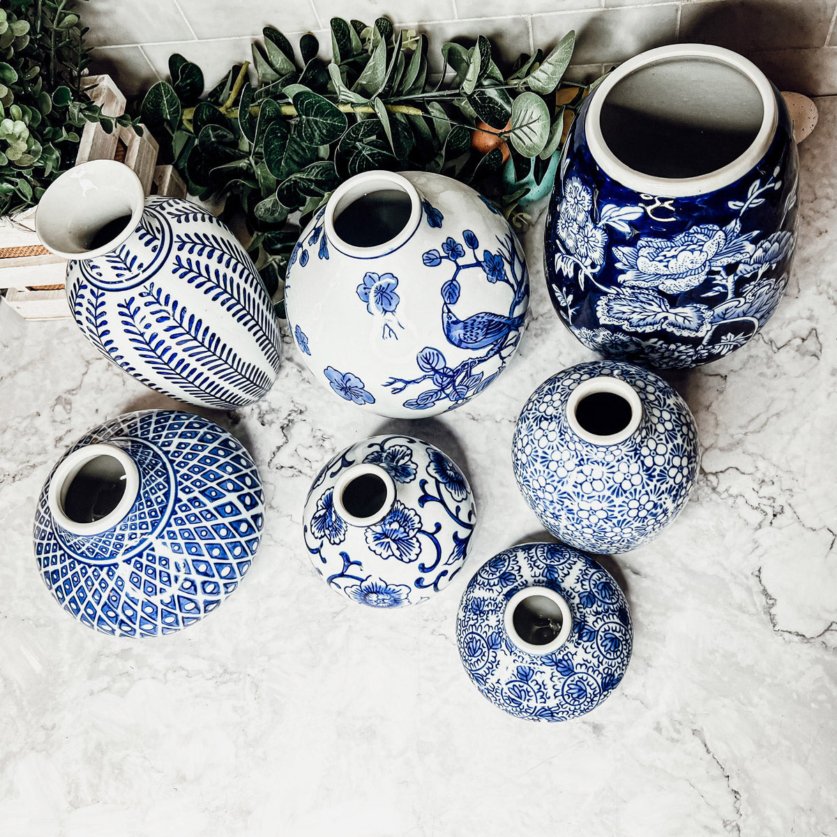 Overhead view of blue and white ceramic vases with open mouths on a light surface