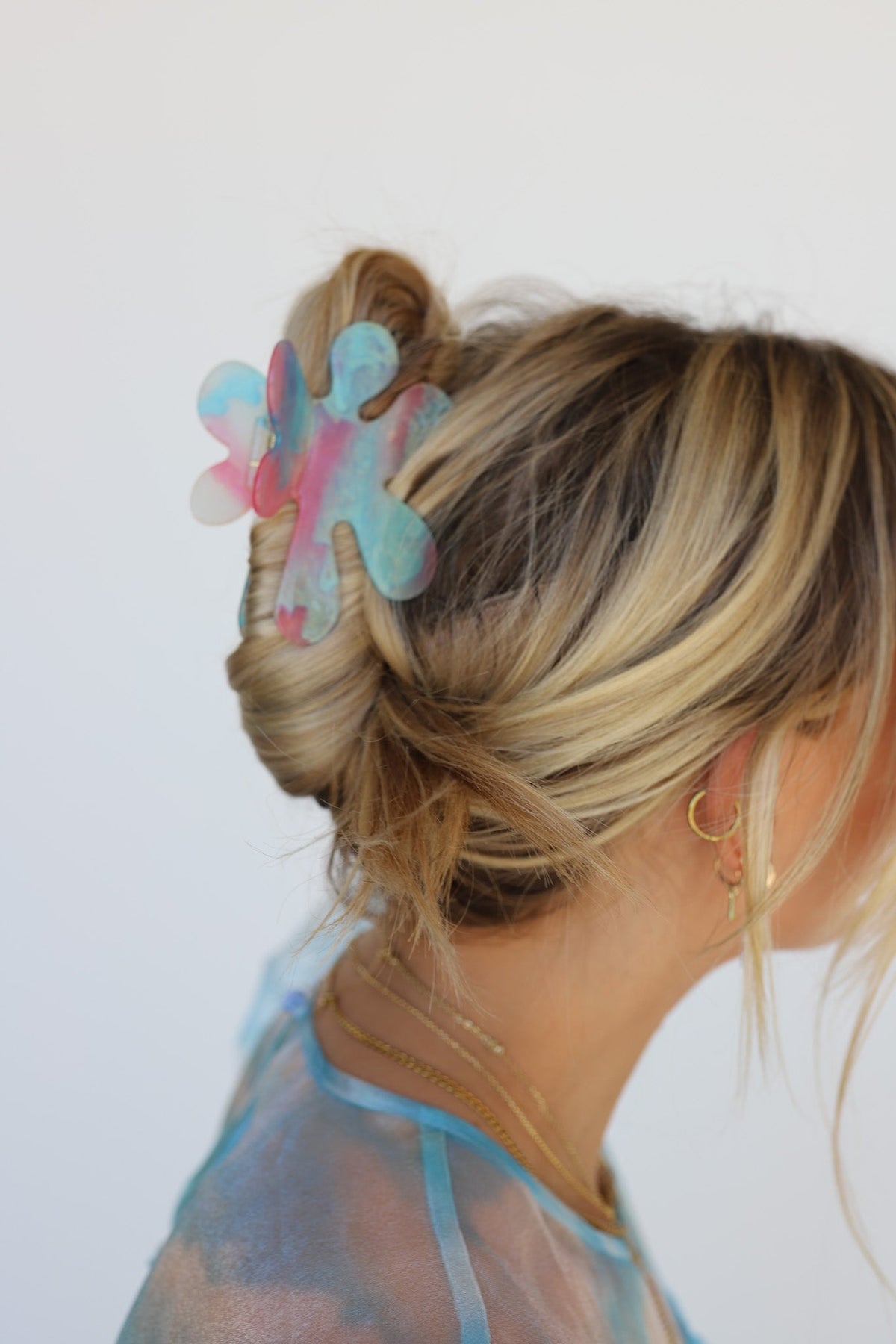 Flower hair claw with iridescent petals clipped in blonde ponytail, side profile