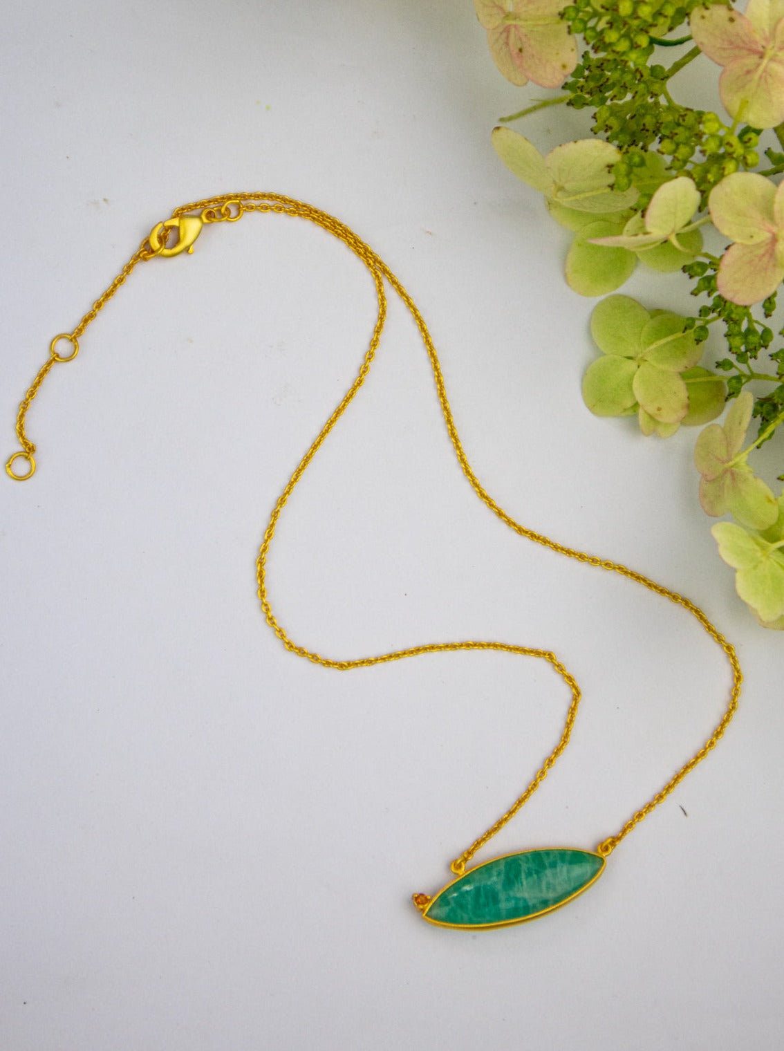 Gold chain necklace with oval blue-teal stone pendant and clasp
