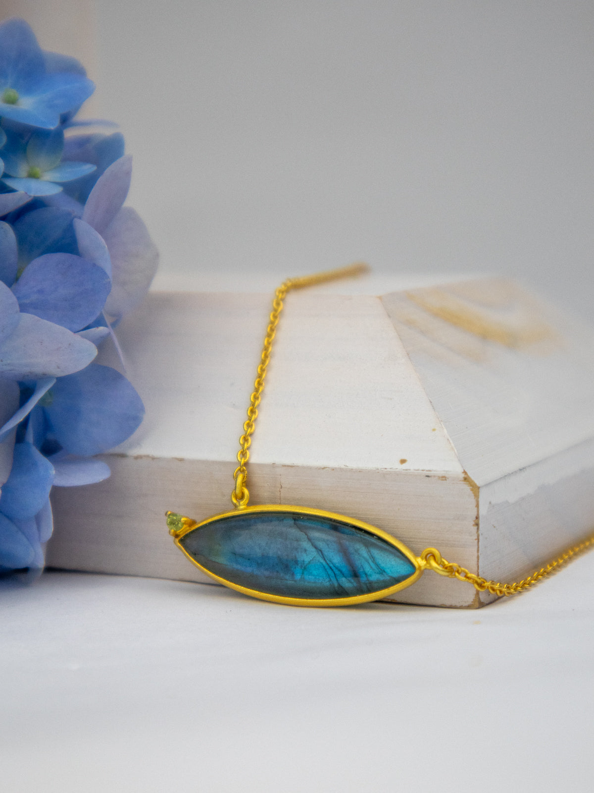Gold chain necklace featuring a large oval blue gemstone pendant