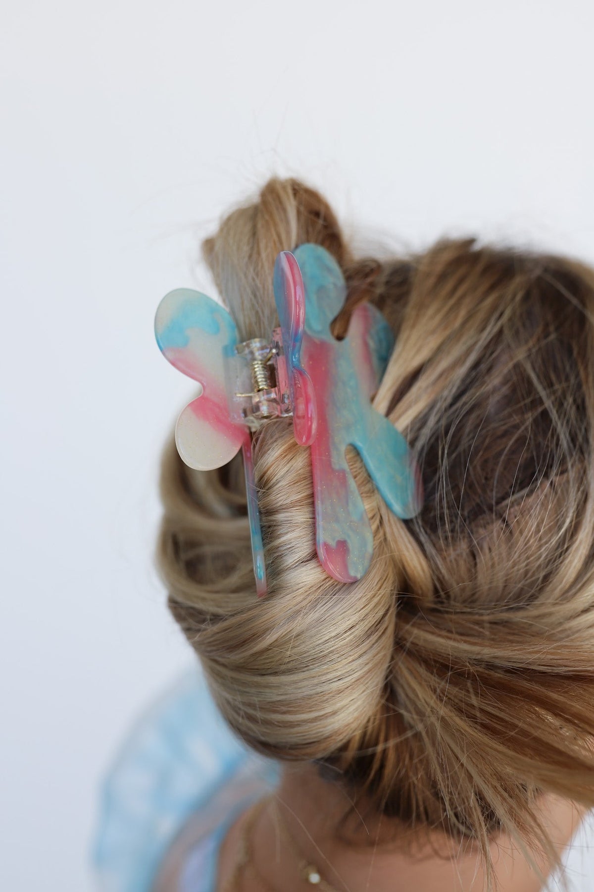 Color-changing hair claw with multicolor pastel butterfly petals on blonde bun
