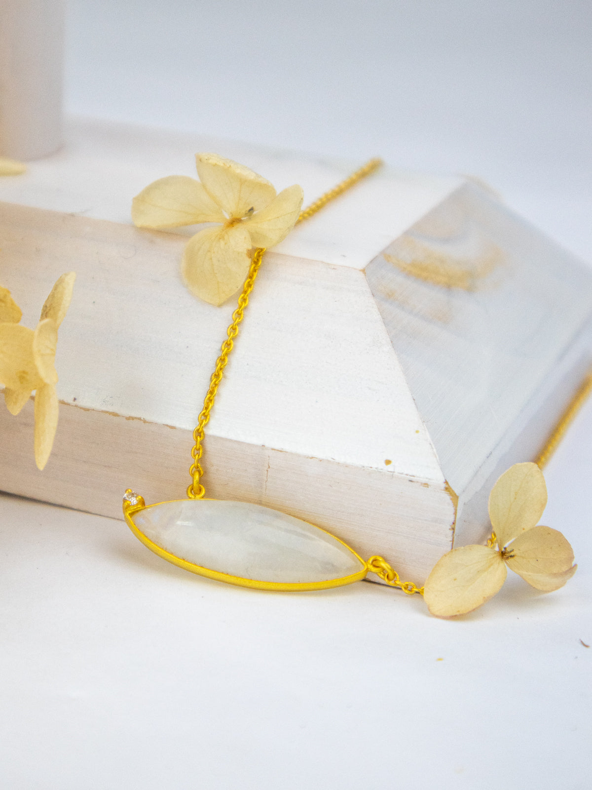 Gold necklace with oval white gemstone pendant and delicate chain