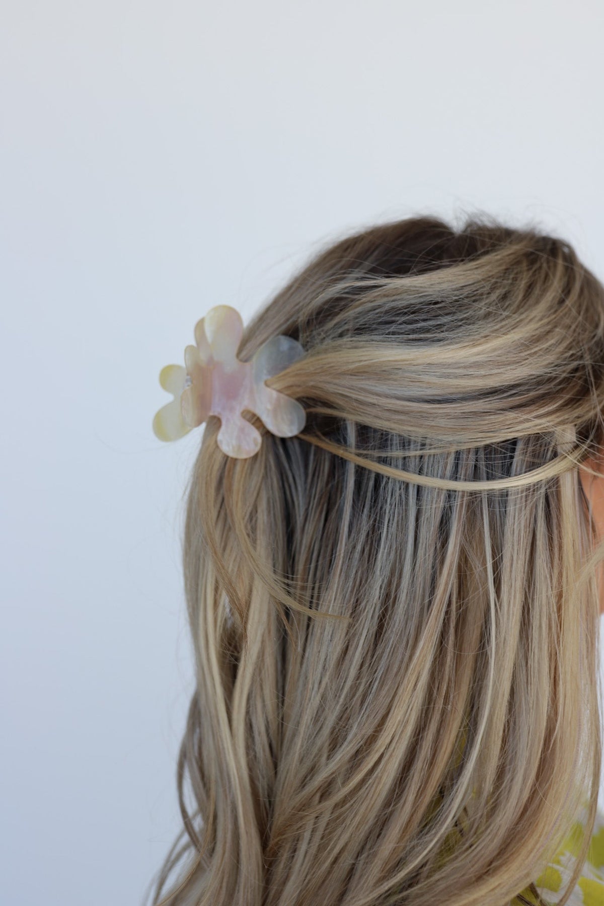 White flower hair claw with iridescent tint in blonde ponytail