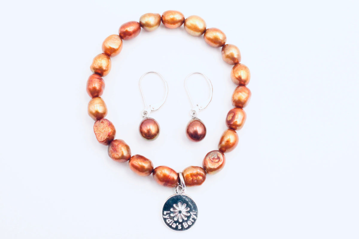 Rust pearl earrings shown with a matching beaded bracelet and charm