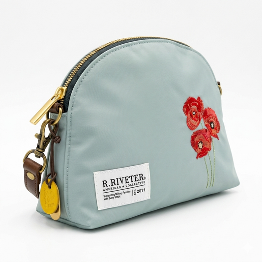 Light blue nylon zip pouch bag with gold zipper, red embroidered flowers, front logo patch