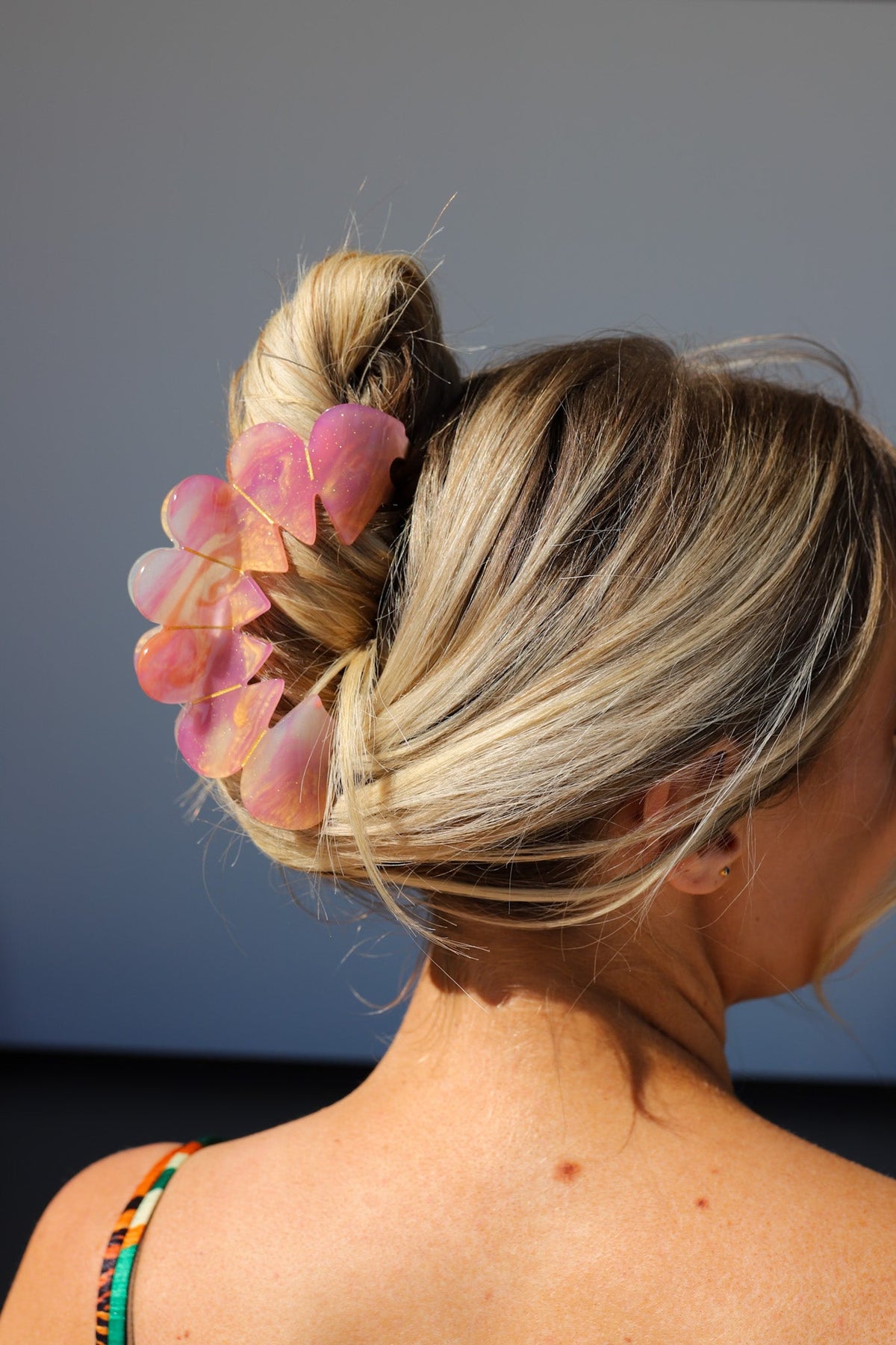 Pastel heart hair claw clip on blonde low bun, side view